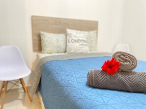 A neatly made bed with a blue quilt, a rolled towel, and a red flower decoration. - Apartment in the Mayakoba area for 8 people, including a SUV, for 7 days (Playa del Carmen)
