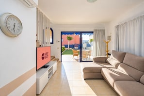 Ein modernes Wohnzimmer mit einer Couch, einem Fernseher und einer Uhr an der Wand.