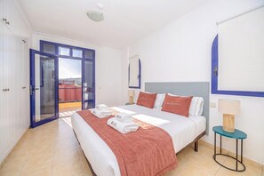 Ein Hotelzimmer mit Bett, einem Nachttisch, einer Lampe und Blick durch eine Glastür.