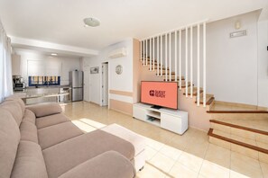Ein modernes Wohnzimmer mit einer Couch, einem Flachbildfernseher und einer Treppe.