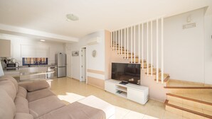 Una sala de estar moderna con sofá, televisor y escalera.