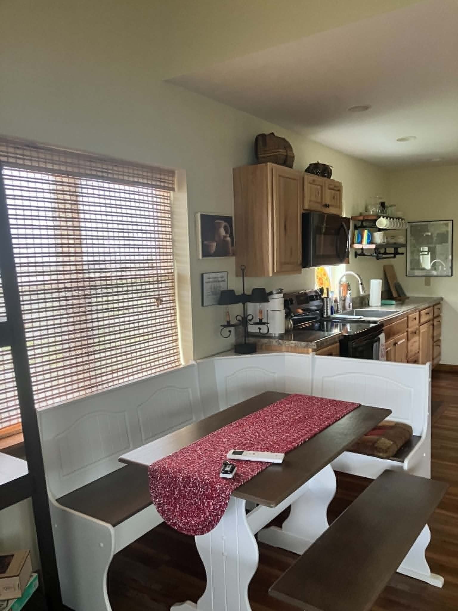 Una cocina con armarios de madera, una encimera y un ventanal con persianas.