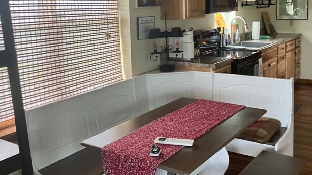Een keuken met houten kastjes, een aanrecht en een raam met zonwering.