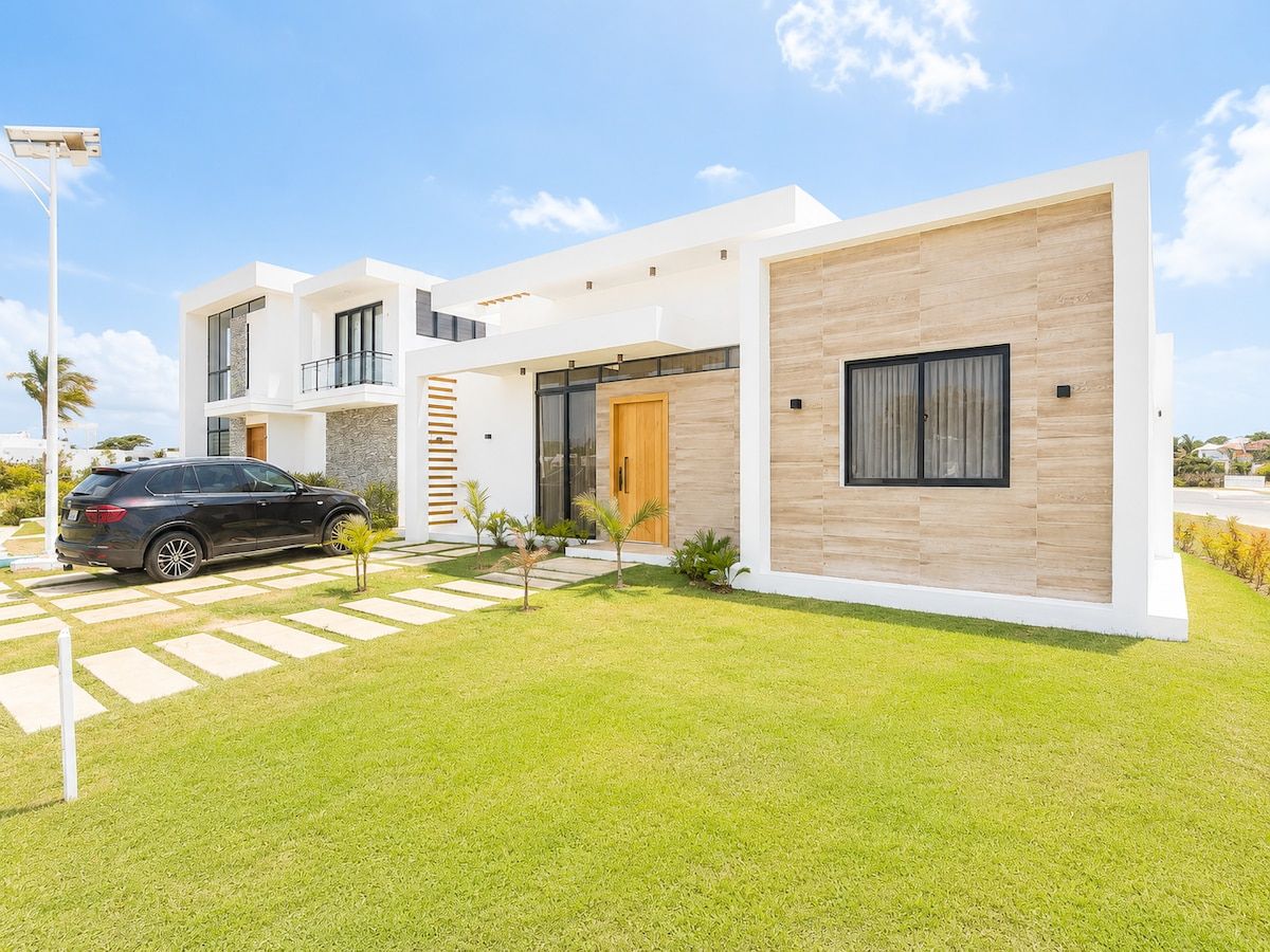 A modern two-story house with a car parked in the driveway, a well-maintained lawn, and a clear sky.