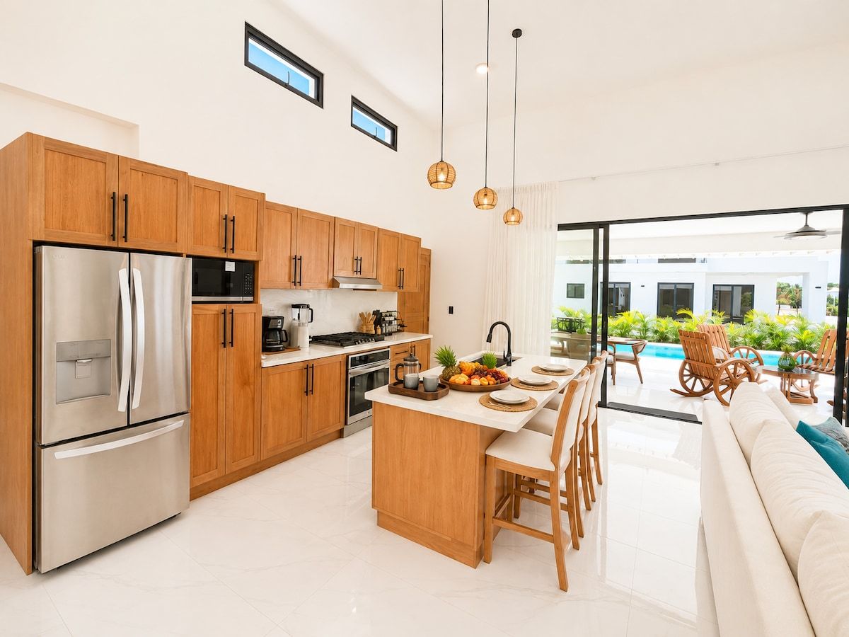 A modern kitchen with stainless steel appliances, wooden cabinets, and a central island with seating.