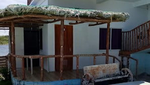 Un edificio de dos pisos con un espacio exterior cubierto y una piscina.