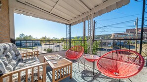 A covered outdoor seating area with a wooden table, two red chairs, and a sofa. - Pet-Friendly Getaway Downtown (Hot Springs)