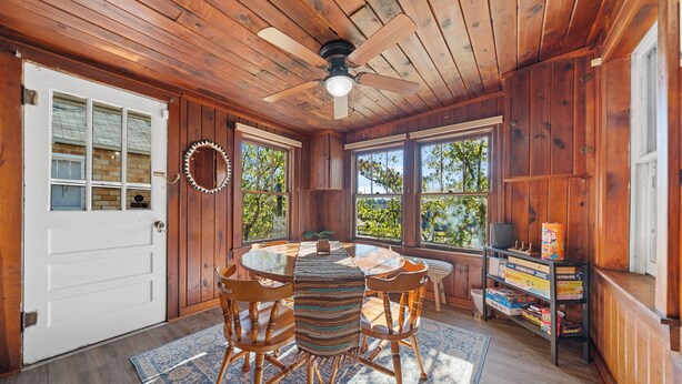 A wooden interior with a round table, chairs, a ceiling fan, and a bookshelf with games. - Pet-Friendly Getaway Downtown (Hot Springs)