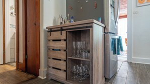 A kitchen with a wooden cabinet containing wine glasses and a stainless steel refrigerator. - Pet-Friendly Getaway Downtown (Hot Springs)