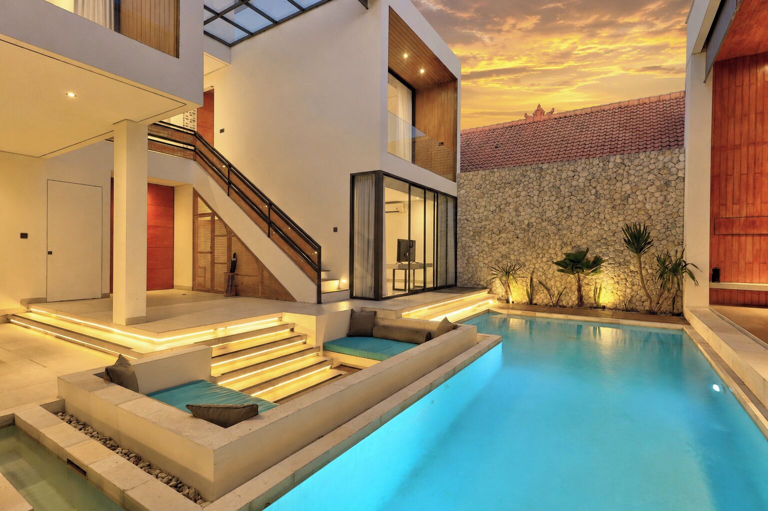 Una casa moderna con piscina, escalera y pared de piedra.