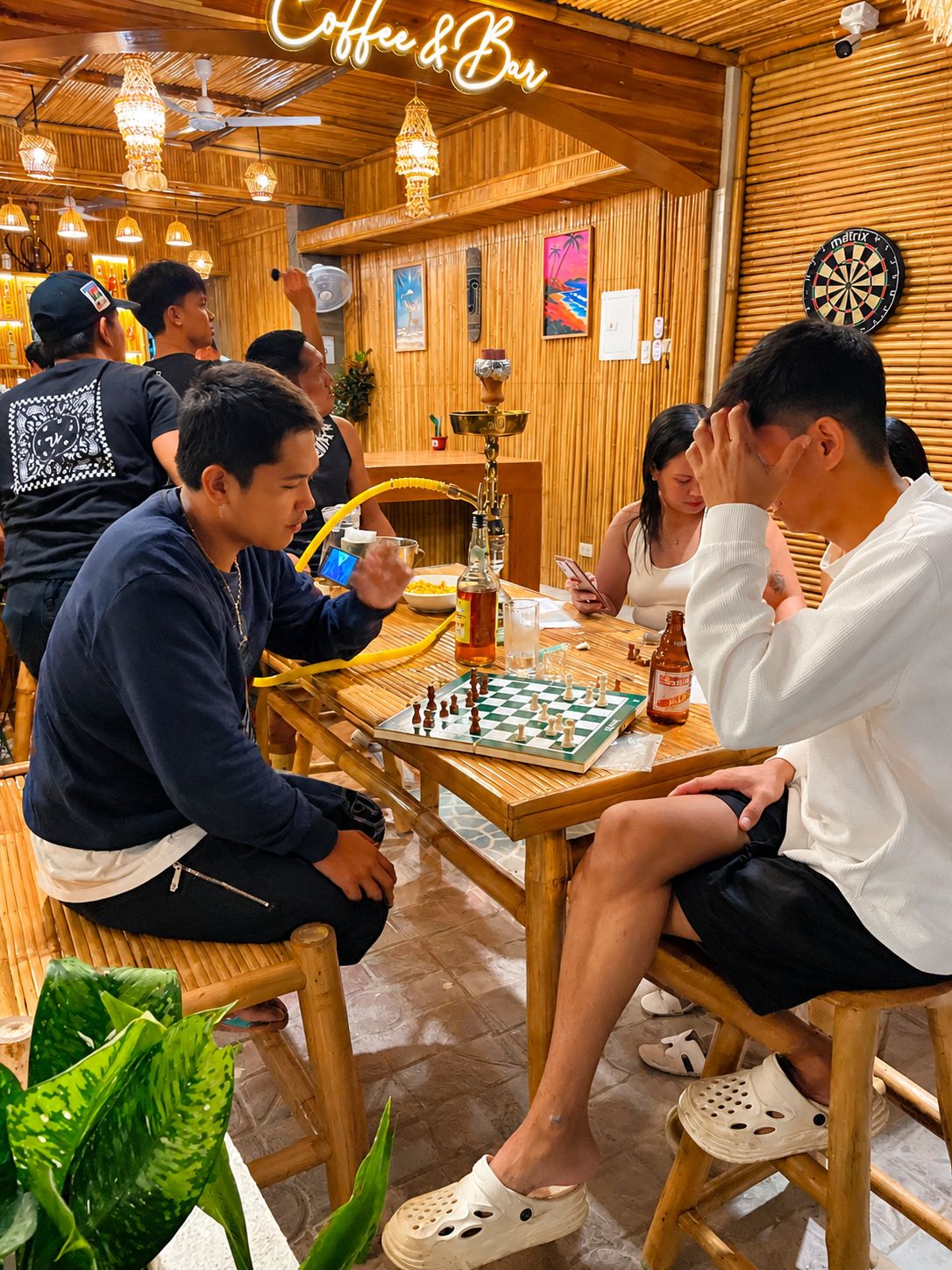 A wooden interior with a chessboard, a hookah, and a dartboard.