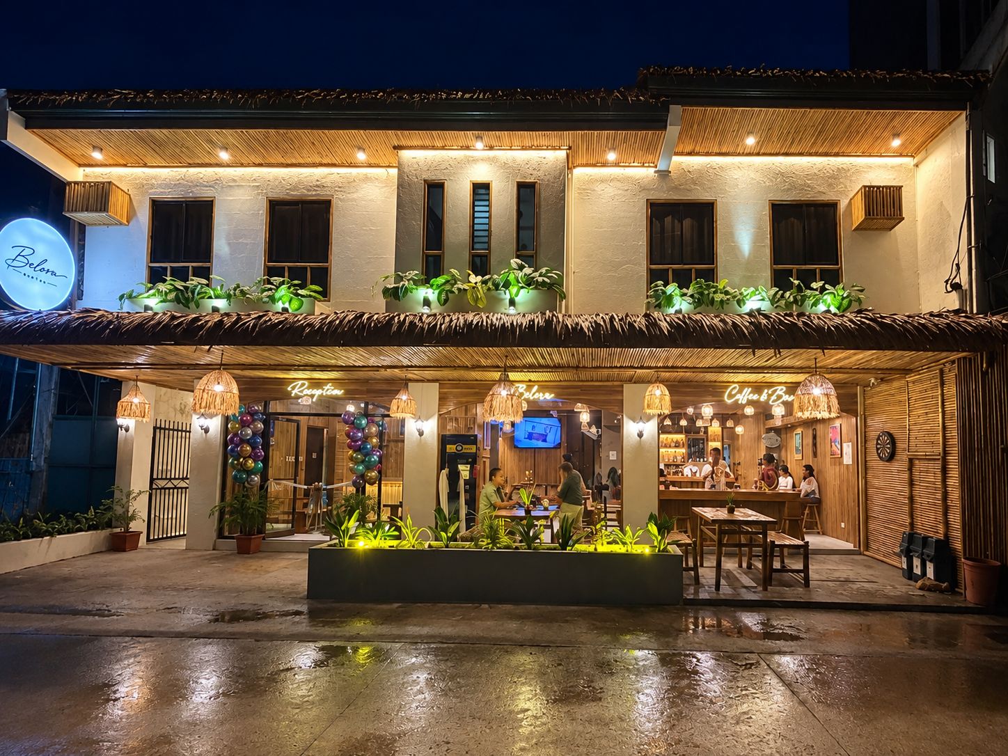 A hotel with a reception area, outdoor seating, and a well-lit entrance.