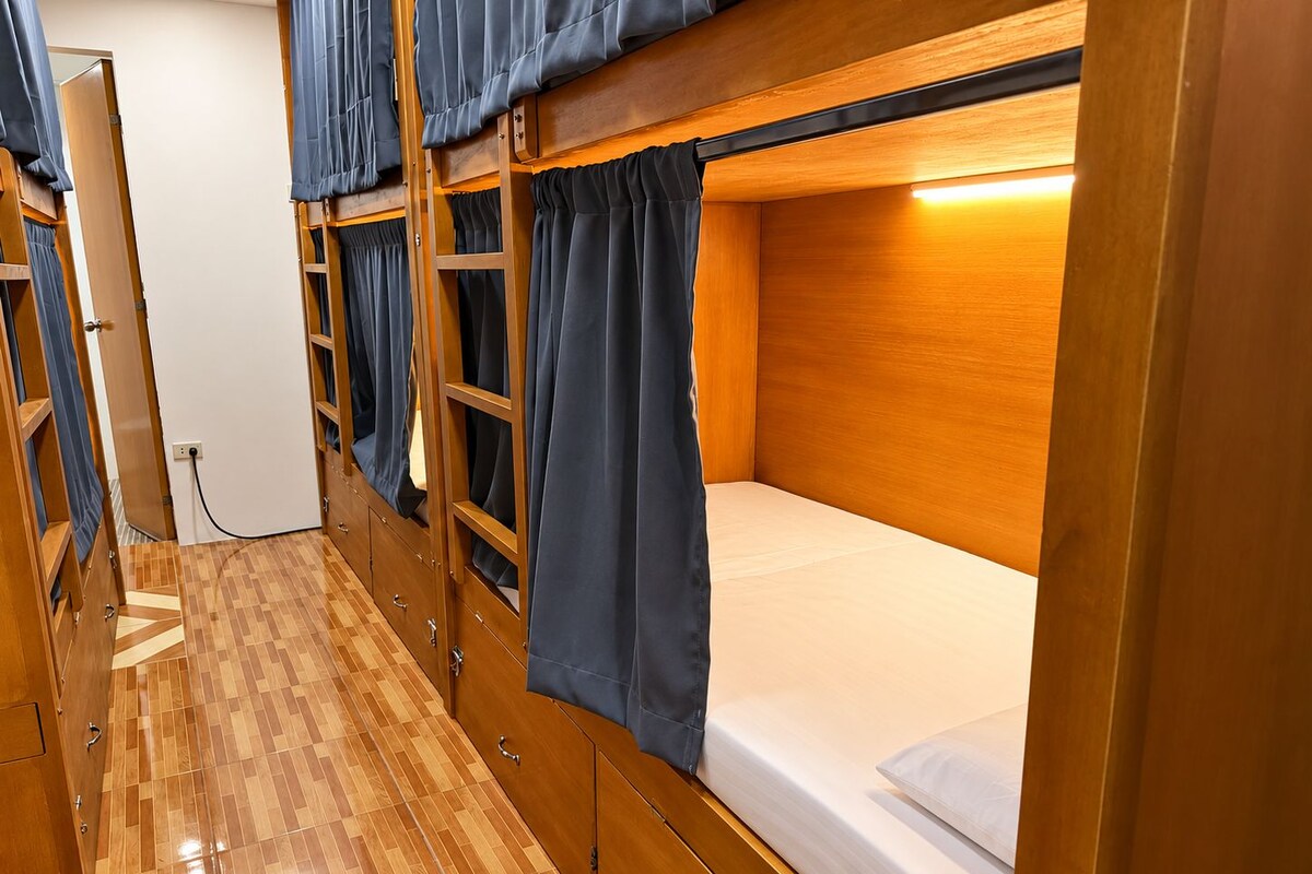 Une chambre avec un lit superposé, un plancher en bois et des rideaux.
