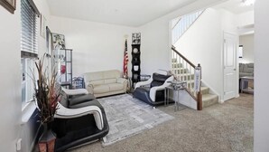 A living room with a sofa, a recliner, a coffee table, and a staircase leading to another level. - Spacious 5BR house in tranquil Wash DC community has Sauna, fitness, and more (Washington)