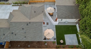 An aerial view of a rooftop patio area with two umbrellas, a small seating area, and a grassy patch. - Entire Private Home with 3 King Beds, Gated Yard, 4 Parking, Ranch Style (La Mesa)