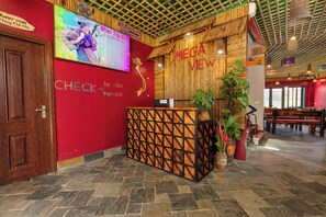 A reception area with a wooden reception desk, a large screen displaying a menu, and a red wall with the text "MEGA VIEW". - Breathtaking Mountain View & Balcony | King Bed (Sa Pa)