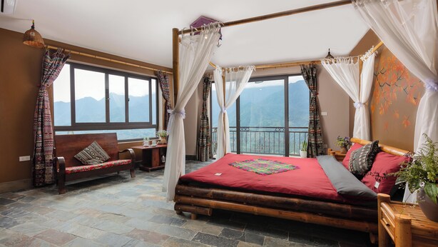 Une chambre avec un lit, un banc et une vue sur les montagnes.