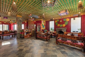 A spacious lobby with wooden benches, a stone pillar, and a colorful mural. - Breathtaking Mountain View & Balcony | King Bed (Sa Pa)