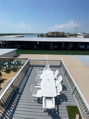 Varanda com mesa e cadeiras, ladeada por guarda-corpo, com vista para a água.