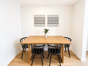 A dining area with a wooden table and four black chairs, a potted plant on the table, and two patterned wall decorations. - Newly Remodeled + Modern Aztec Themed + 1 Bed/1 Bath Near Airport (Lansing)