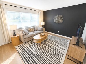 Una sala moderna con un sofá, una mesa de centro y un televisor sobre un mueble.