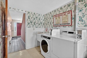 A laundry room with a washing machine, a dryer, and a sign indicating laundry room hours. - Newly Remodeled + Modern Aztec Themed + 1 Bed/1 Bath Near Airport (Lansing)