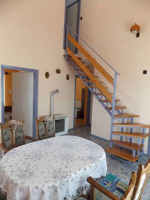 A room with a round table covered with a lace tablecloth, a wooden staircase, and a radiator. - Holiday home with large garden, garden pavilion and barbecue (Zalakaros)