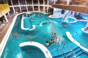 An indoor swimming pool with multiple lanes, a hot tub, and a slide.