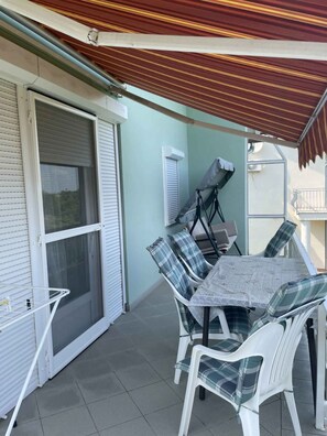 An outdoor patio with a table and chairs, a sliding glass door, and a covered area.