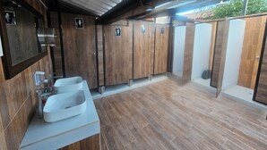 Un baño moderno con paneles de madera, dos lavamanos y un separador de vidrio para el área del inodoro.