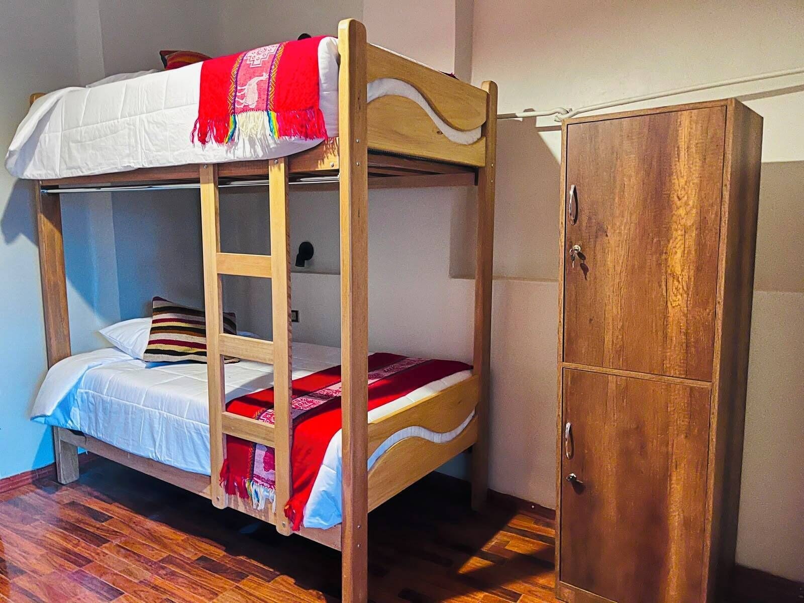 A bunk bed with a ladder, a wooden wardrobe, and a striped pillow.