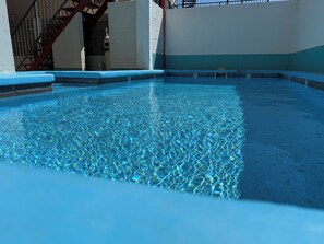 Ein klares Hallenbad mit blau gefliestem Boden, umgeben von Wänden und einer Treppe.