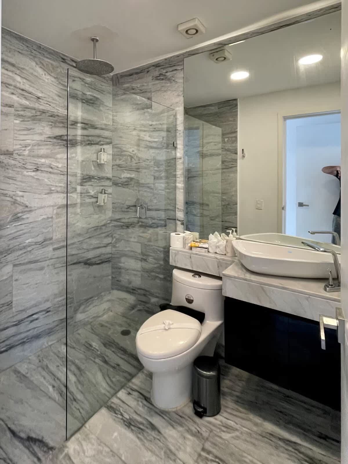 A modern bathroom with a glass-enclosed shower, a toilet, and a sink.