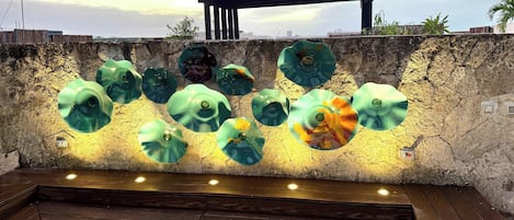 A pool area with a stone wall and multiple green glass sculptures.
