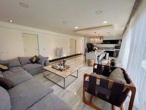 A modern living room with a sofa, coffee table, and a dining area with chairs. - Black House - Modern 3BR Villa with Private Pool (Tulum)