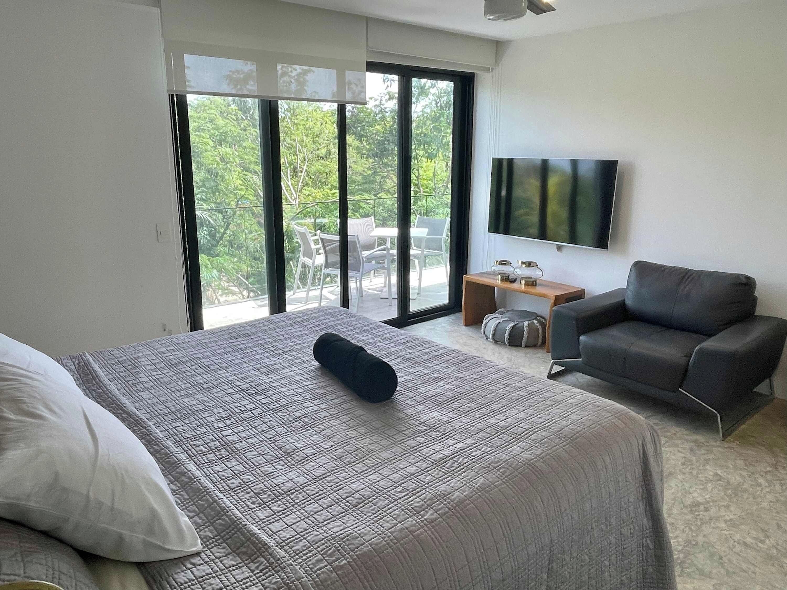 Une chambre d’hôtel comprenant un lit, un canapé, une télévision et un balcon aménagé avec du mobilier d’extérieur.