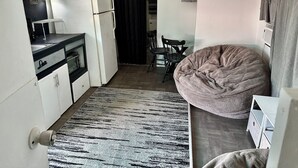 A compact kitchen with a refrigerator, microwave, and a dining area with a chair and table. - Cozy lil 1 bedroom getaway (Rockport)