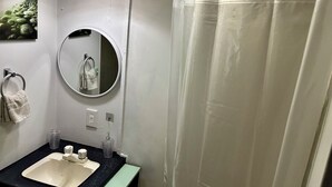 A bathroom with a sink, mirror, and shower curtain. - Cozy lil 1 bedroom getaway (Rockport)