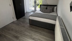 Ein Schlafzimmer mit Bett, Heizkörper, Kleiderschrank und einer Glastür zum Außenbereich.