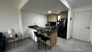 Eine moderne Küche mit einer zentralen Kochinsel, schwarzen Barhocker, einer Mikrowelle und einem Kühlschrank.