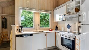 A modern kitchen with white cabinetry, a built-in oven, and a window overlooking greenery. - "Ljubinko" - 300m from the sea by Interhome (Sydals)