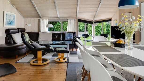 A modern living room with a sofa, chairs, a dining table, and a large window offering a view of greenery. - "Ljubinko" - 300m from the sea by Interhome (Sydals)