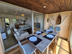 A modern dining area with a table set for four, a sofa, and a hammock. - Bright 2-Bedroom Apartment with Sea Views, Wi-Fi and Parking (ST MANDRIER SUR MER)