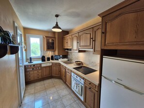 A kitchen with wooden cabinets, a built-in oven, a sink, and a refrigerator. - Bright 2-Bedroom Apartment with Sea Views, Wi-Fi and Parking (ST MANDRIER SUR MER)