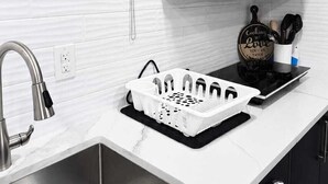 Une cuisine moderne dotée d’un évier à deux bacs, de meubles noirs, d’une hotte en acier inoxydable et d’un four à micro-ondes.