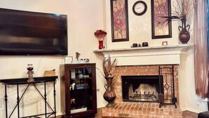 Un soggiorno con camino, una TV a schermo piatto montata a parete e un elegante ripiano decorativo.