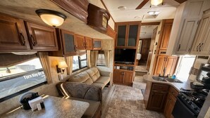 Een compact camperinterieur met een kitchenette, een zithoek en een televisie.