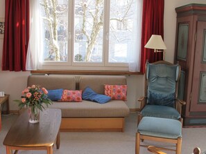 A room with a sofa, a chair, a table, and a window with curtains. - Quadra / Masé-Goldberg, (Flims Dorf), 1030 by Interhome (Flims)