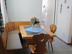 A dining area with a wooden table, chairs, a bench, and a vase with flowers. - Quadra / Masé-Goldberg, (Flims Dorf), 1030 by Interhome (Flims)