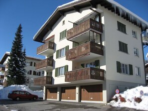 A multi-story building with balconies, a car parked in front, and snow on the ground. - Quadra / Masé-Goldberg, (Flims Dorf), 1030 by Interhome (Flims)